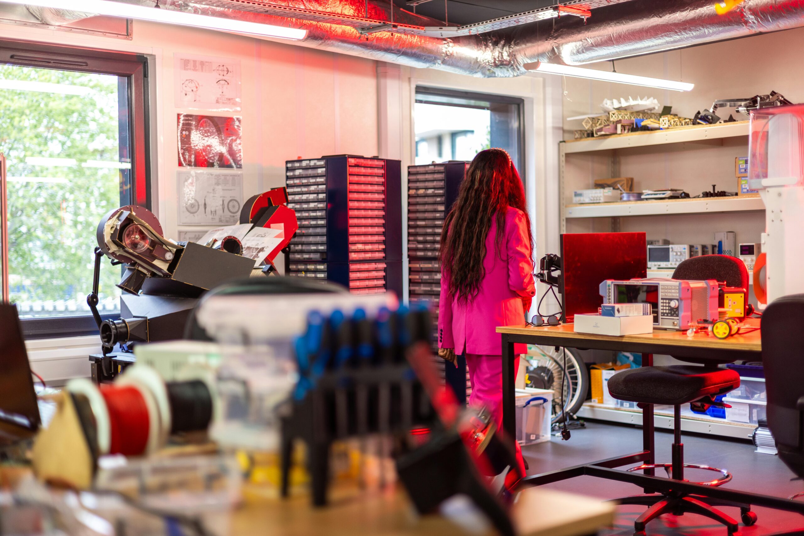 A woman in a pink suit exploring a colorful and modern laboratory environment.
