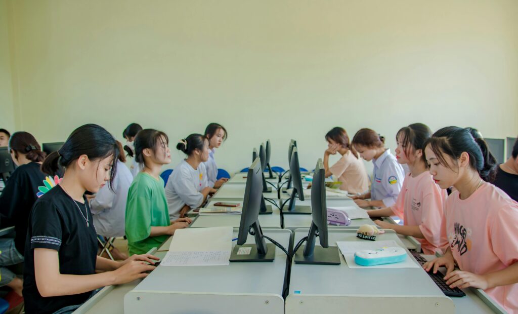 Group of female students studying at computers in a classroom setting.